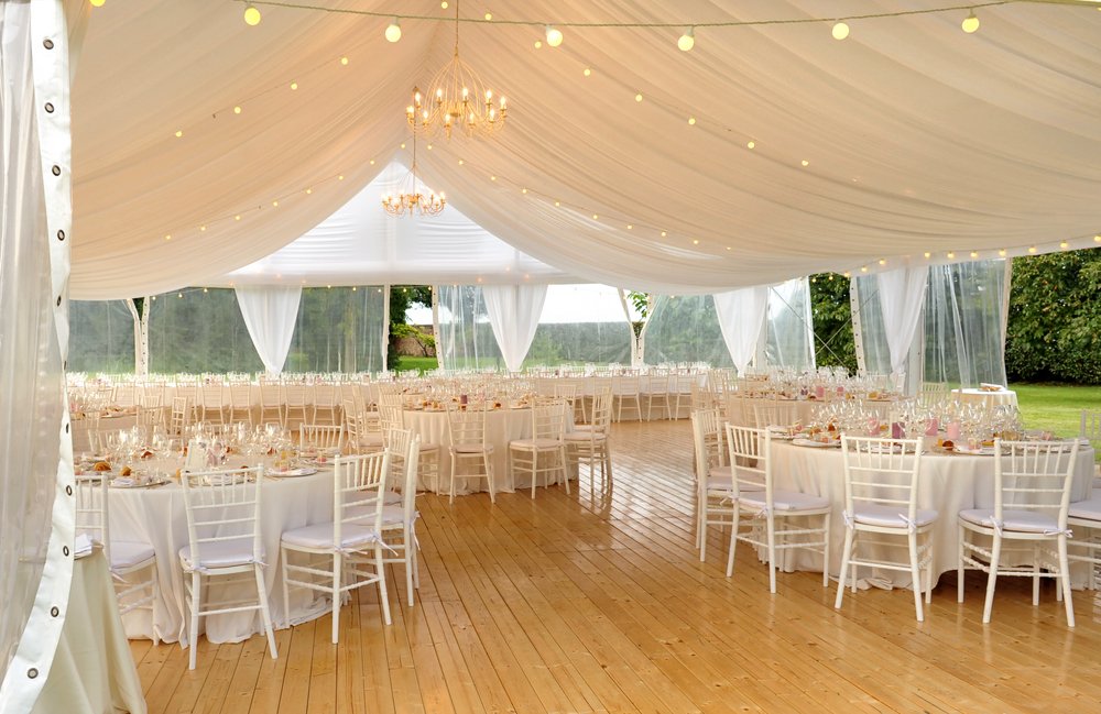 An outdoor wedding venue with a big white tent overhanging it